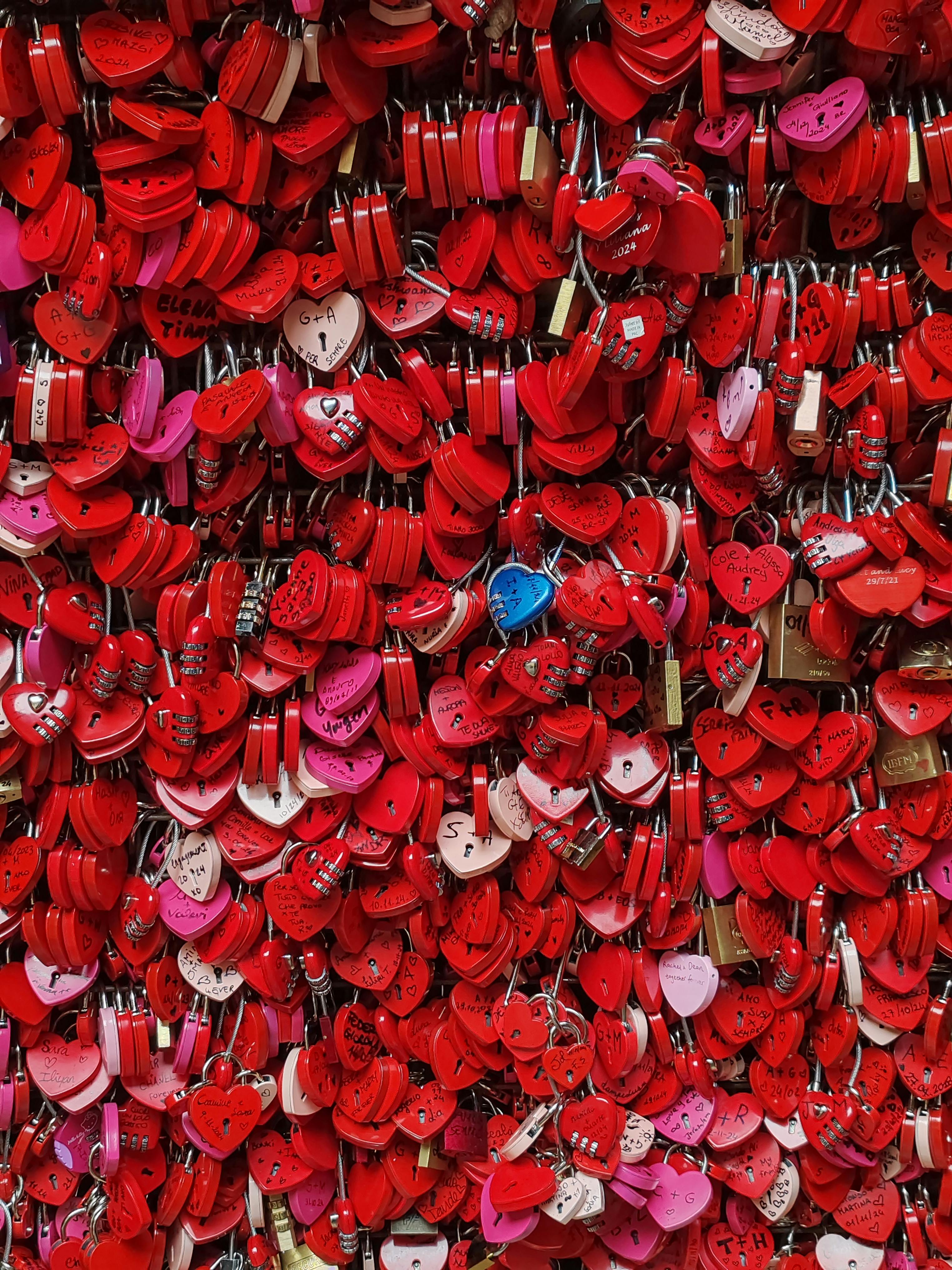 A vibrant collection of red and pink heart-shaped padlocks symbolizing love and unity.