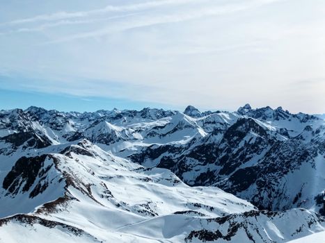 Panoramic view of snow-covered mountain peaks under a clear blue sky.