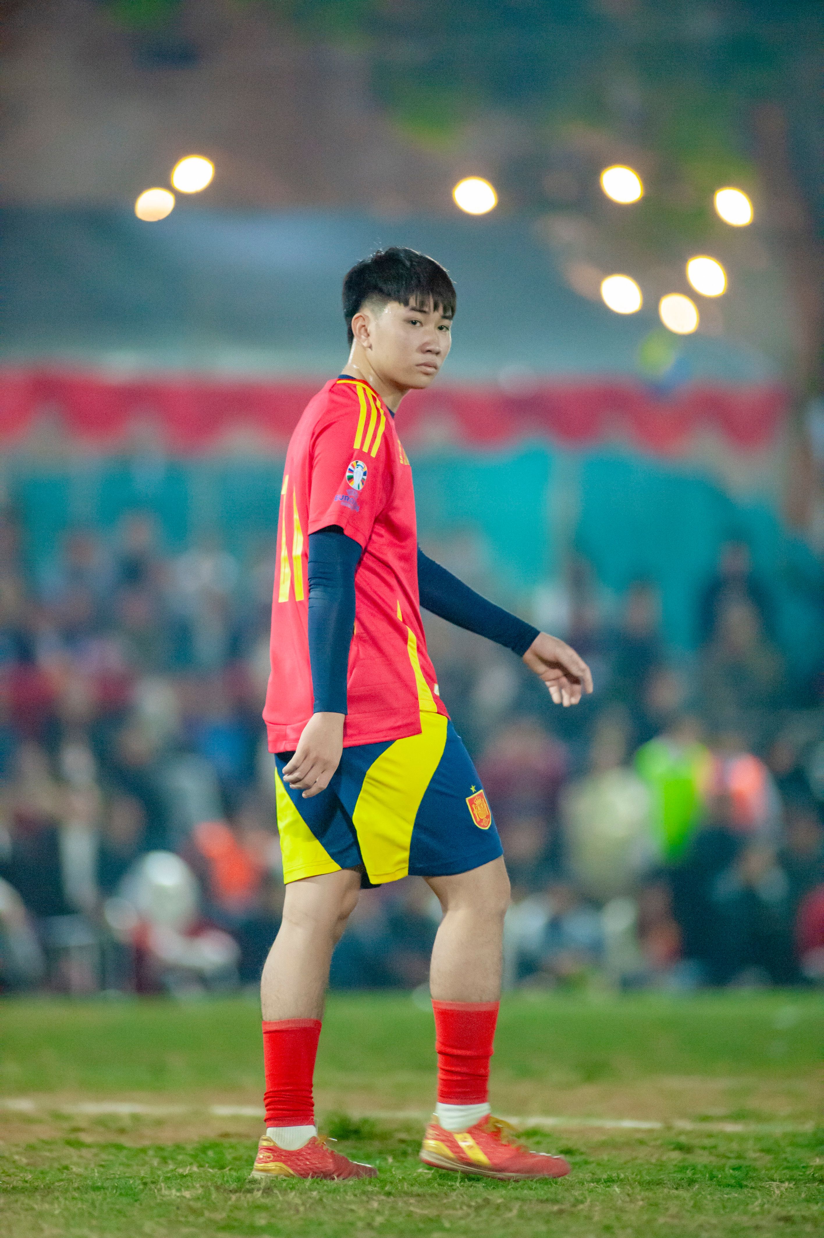 Young athlete in vibrant soccer uniform during an evening match in Hà Nội.