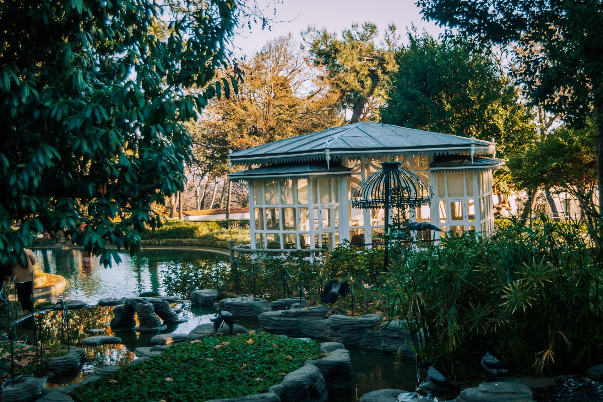 Peaceful garden pavilion surrounded by lush greenery and a calm pond.