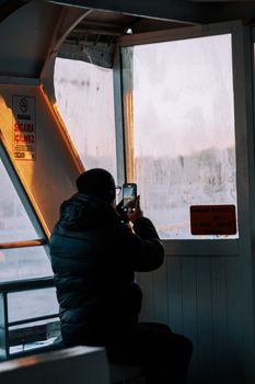 A person captures a beautiful sunset through a ferry window, highlighting a moment of travel and reflection.