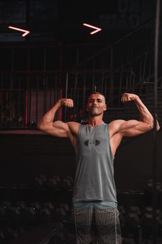 Athletic man posing and flexing muscles in a dimly lit gym.