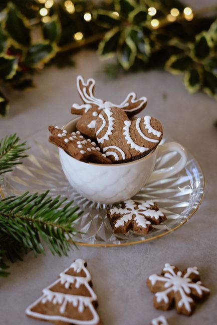 Festive gingerbread cookies in dainty teacup with holiday decorations.