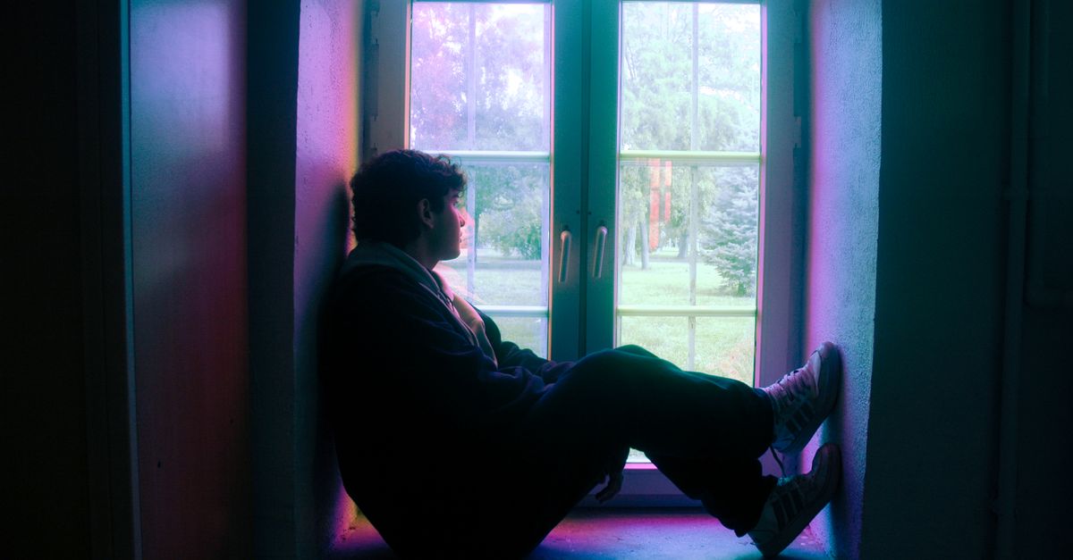 Person in silhouette sitting by a window with colored glass in Istanbul.