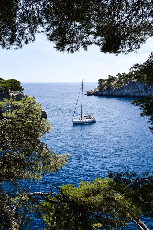 Free Idyllic view of a sailboat cruising in the crystal blue waters of Provence's Calanques. Stock Photo