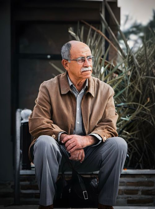 Free Portrait of a thoughtful senior man sitting outdoors in Algeria, wearing a brown jacket. Stock Photo
