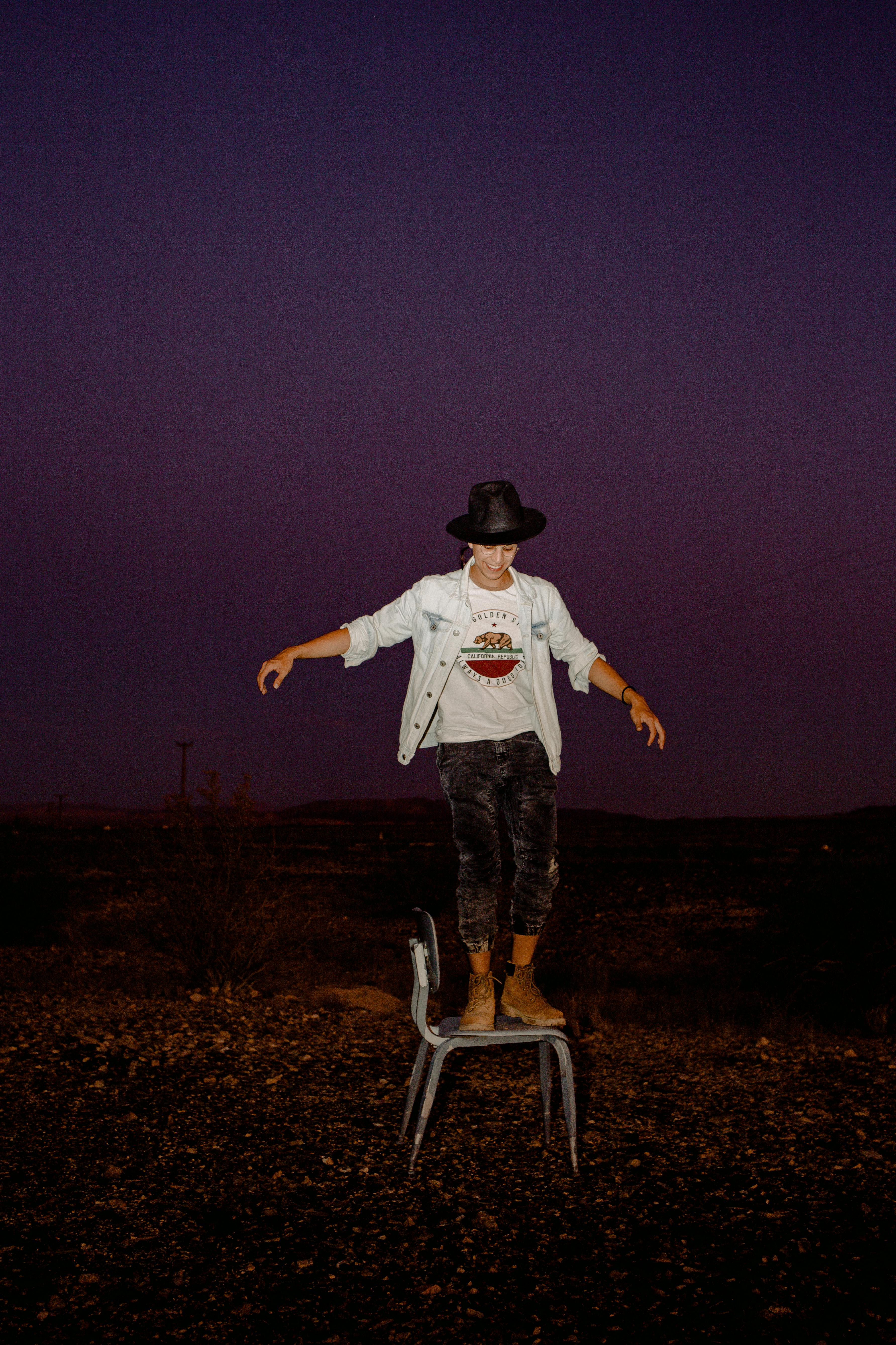 戴着牛仔帽的年轻人在星空下的椅子上保持平衡，显得既有趣又时尚