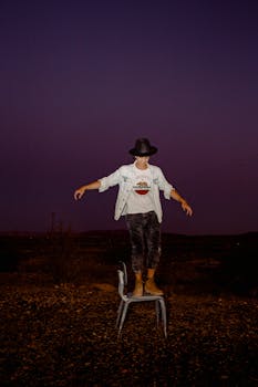 戴着牛仔帽的年轻人在星空下的椅子上保持平衡，显得既有趣又时尚