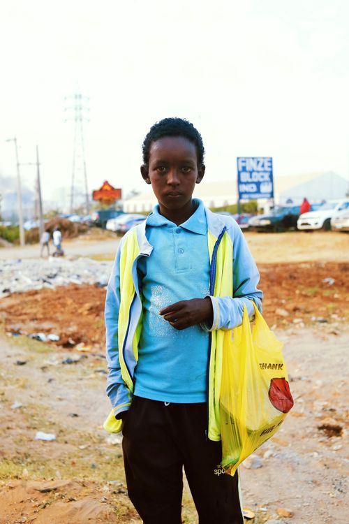 Free Young boy holding a bag in an outdoor market scene in Abuja, Nigeria. Stock Photo