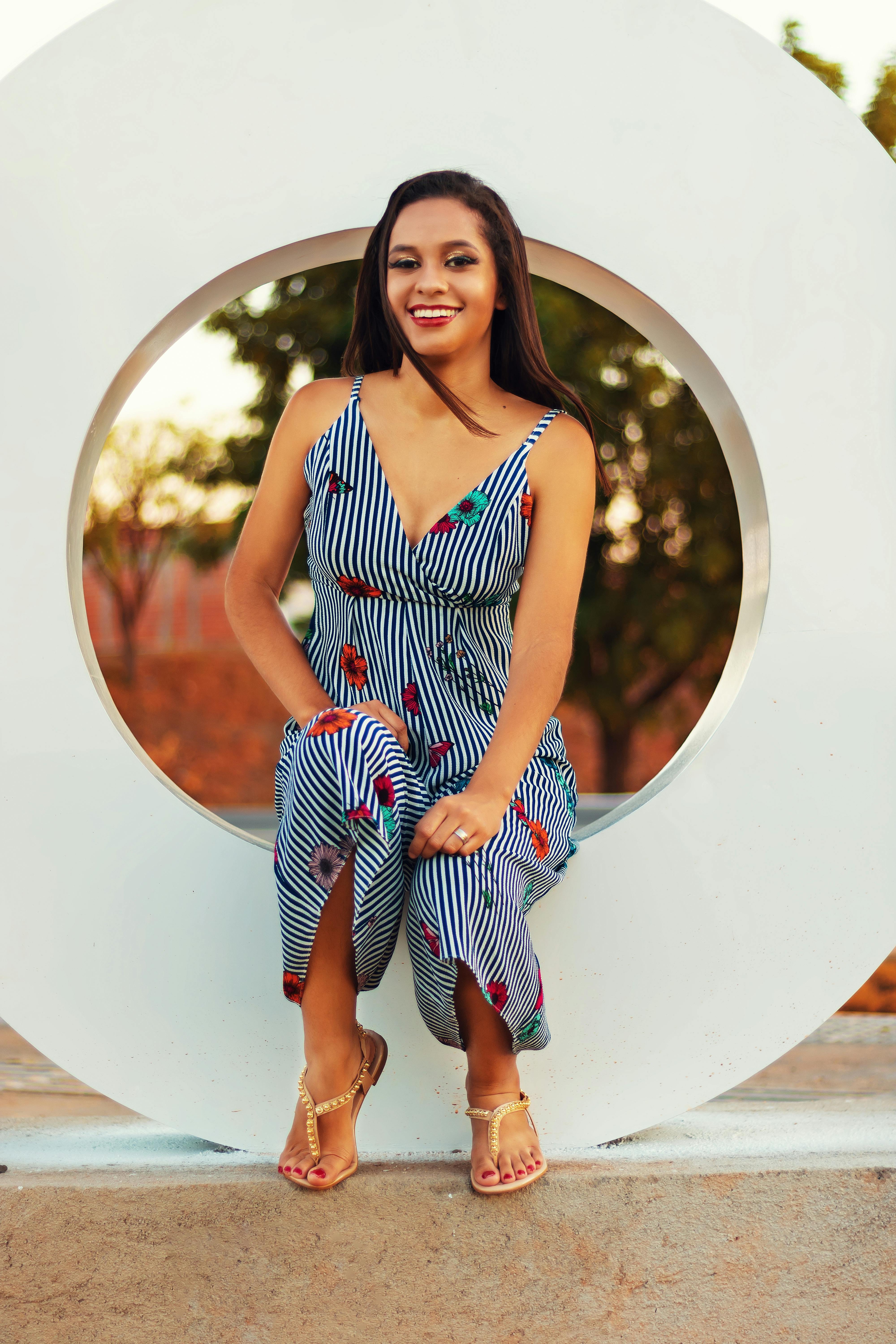 一位快乐的女子穿着时尚的条纹连衣裙，坐在抽象的背景下微笑