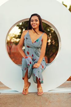 一位快乐的女子穿着时尚的条纹连衣裙，坐在抽象的背景下微笑