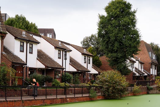 Brick and timber houses by a lush canal in London, offering a peaceful suburban atmosphere.