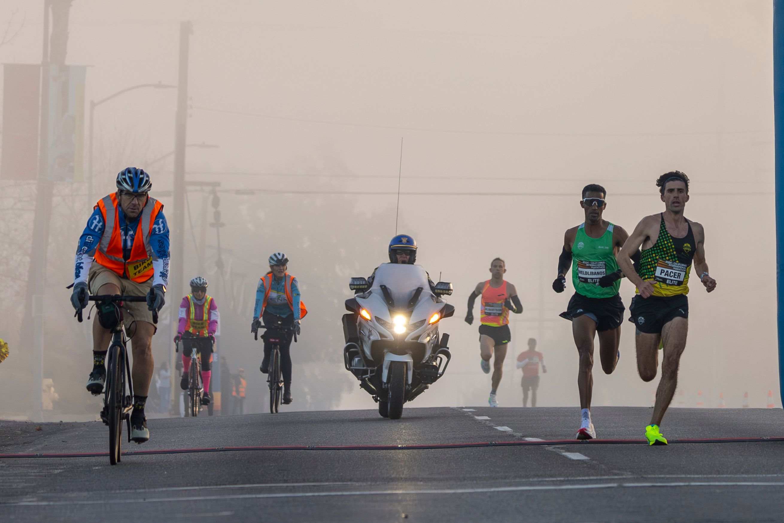 Marathon Runners with Cyclist Escorts in Foggy Race · Free Stock Photo