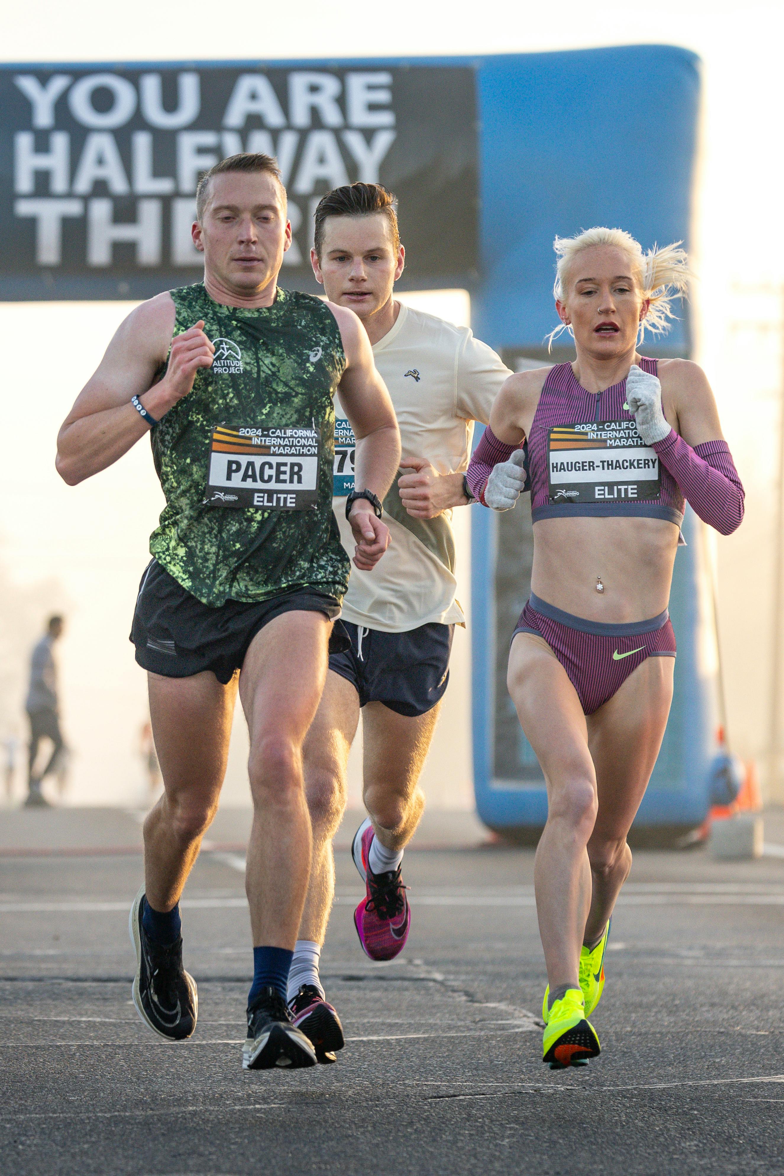 Elite marathon runners passing the halfway point during a race, demonstrating focus and endurance.