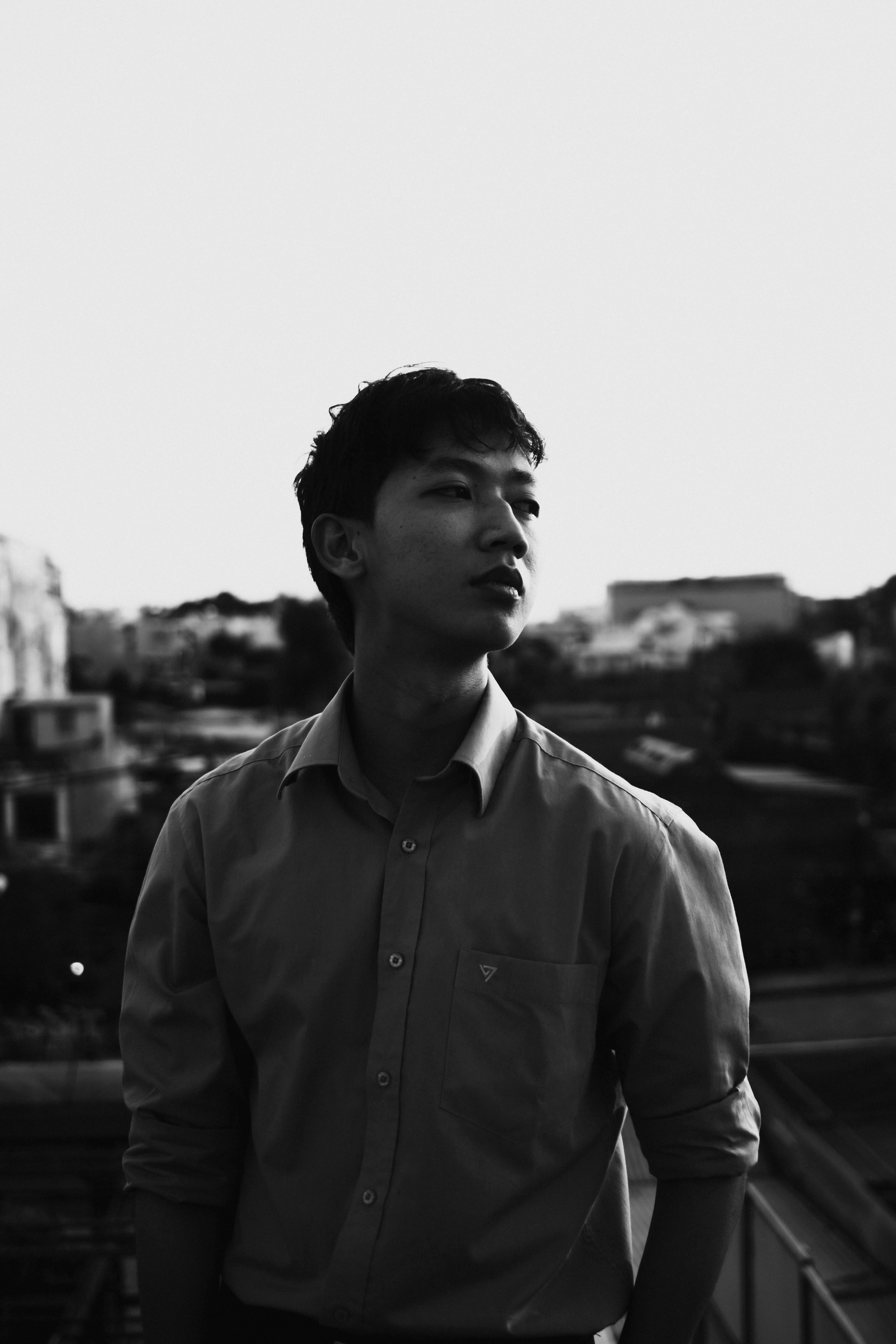 Moody black and white portrait of a young man looking contemplative outdoors.