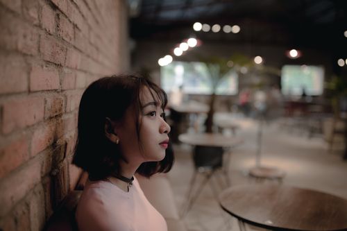 Free Young woman in a cozy cafe with soft lighting, creating a warm and introspective atmosphere. Stock Photo