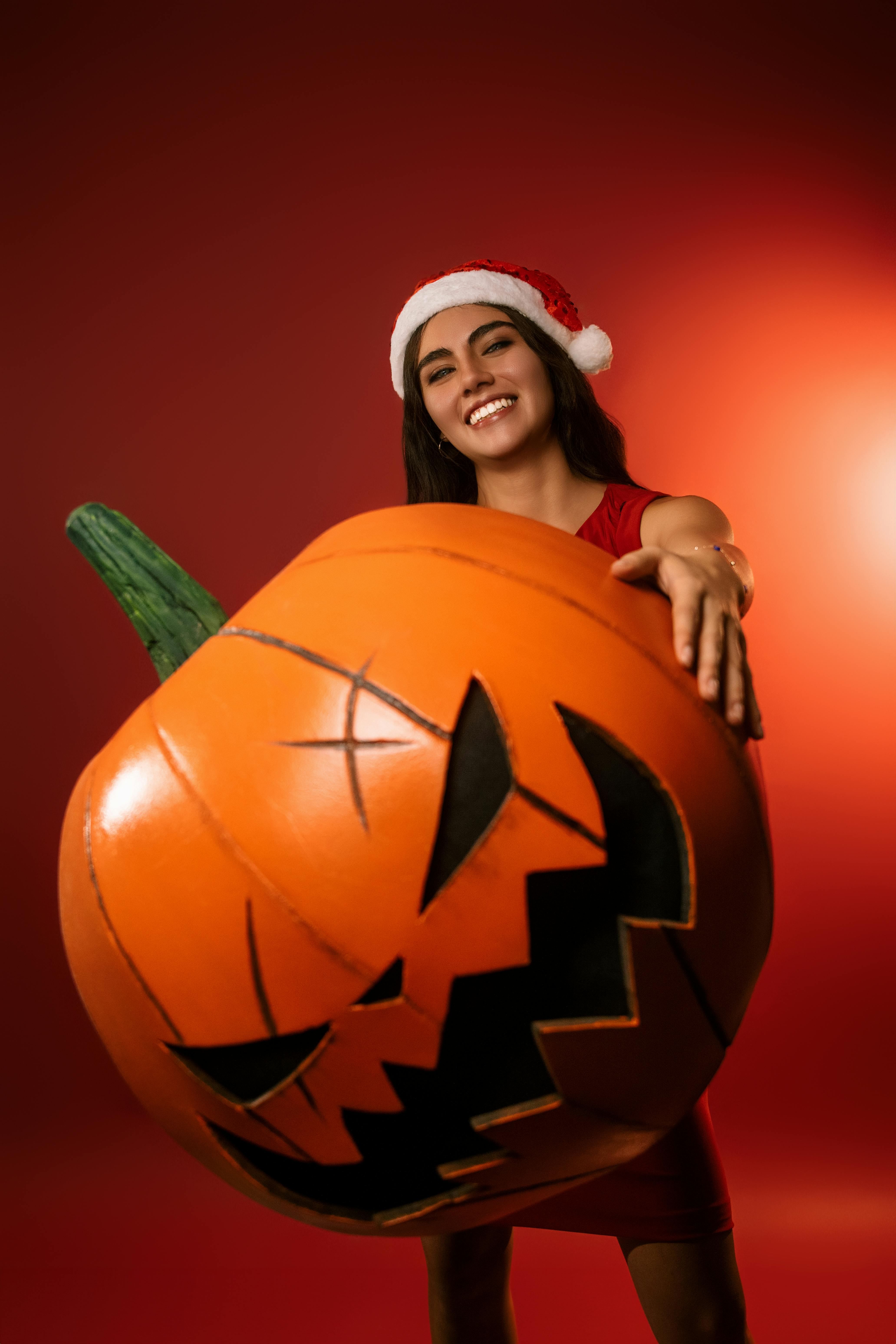 festive woman with santa hat holding pumpkin