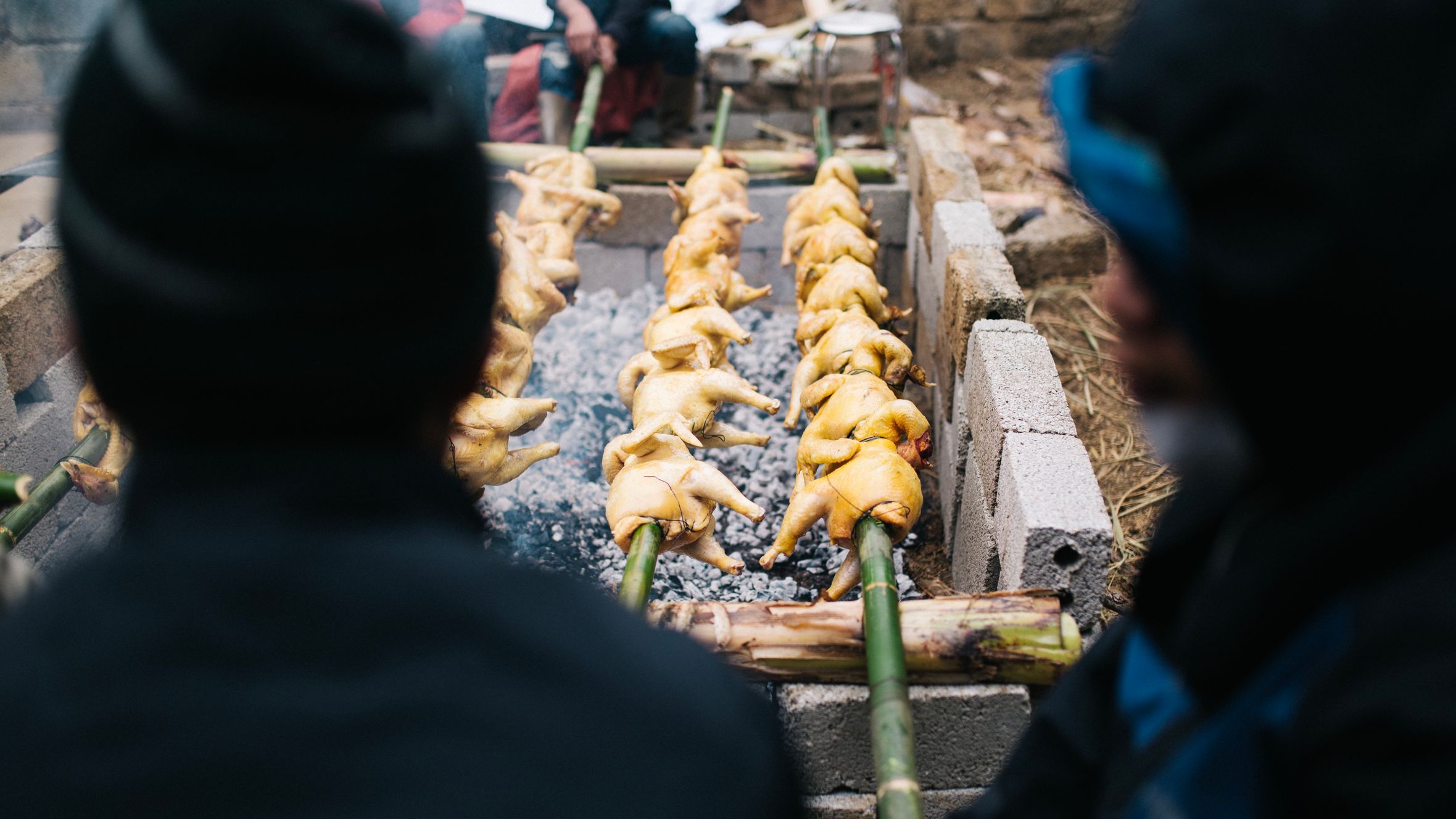 Spit-roasting chickens over coals in Lạng Sơn, Vietnam, showcasing local culinary tradition.