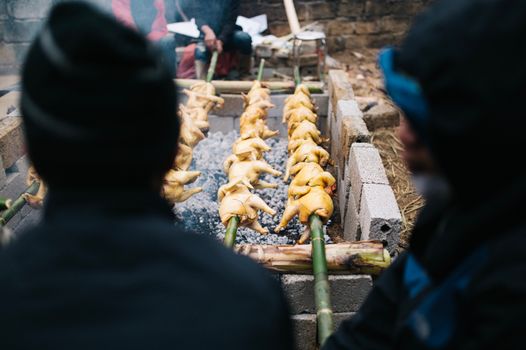 Spit-roasting chickens over coals in Lang Son, Vietnam, showcasing local culinary tradition.