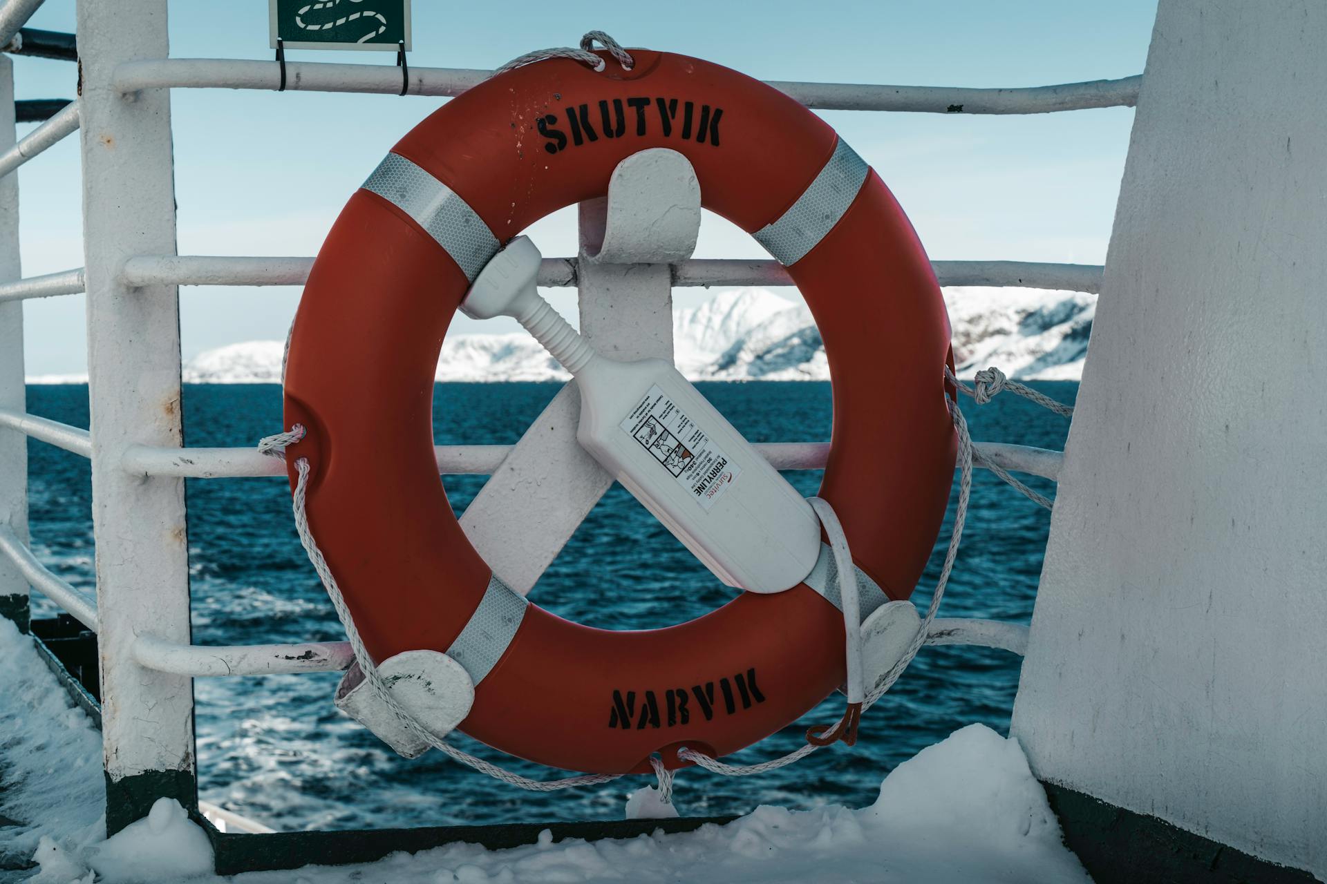 Lifebuoy on a ferry in Norway, with snow and ocean backdrop conveying winter travel.