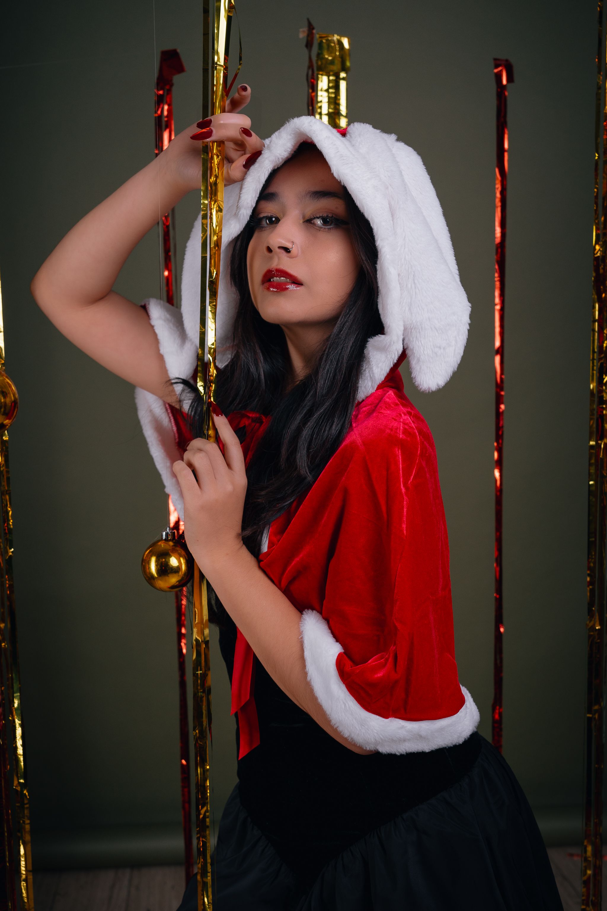Stylish woman in Santa attire surrounded by festive decor, perfect for holiday themes.