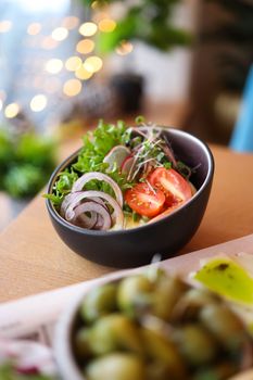 Colorful vegetable salad bowl with fresh ingredients like tomatoes, lettuce, and onions on a wooden table.
