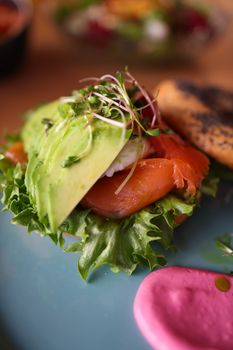 Delicious open-faced bagel with avocado, salmon, and microgreens