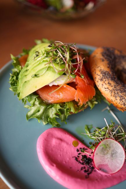 Tasty bagel topped with smoked salmon, avocado, sprouts, and beet sauce. Perfect for a healthy brunch.