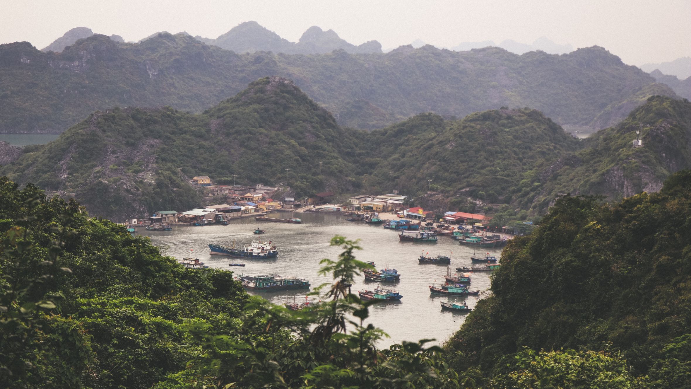 A picturesque view of fishing boats nestled among lush green hills in Hai Phong, Vietnam.