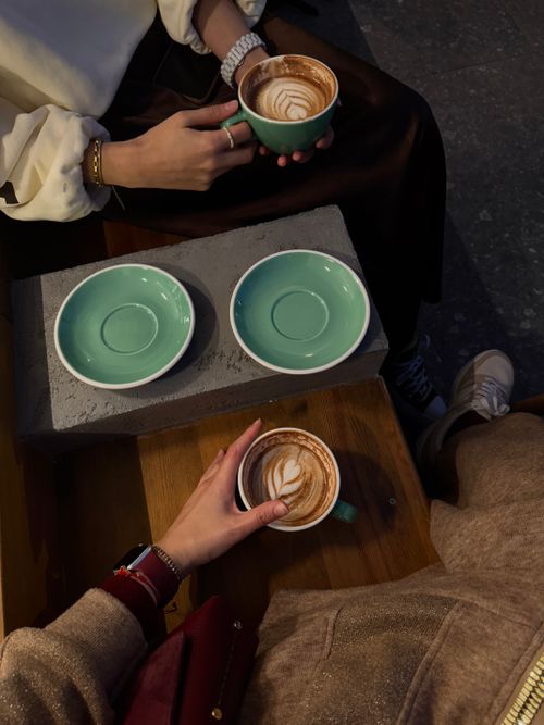 Free Two people enjoying cappuccinos at a cozy cafe setting. Stock Photo