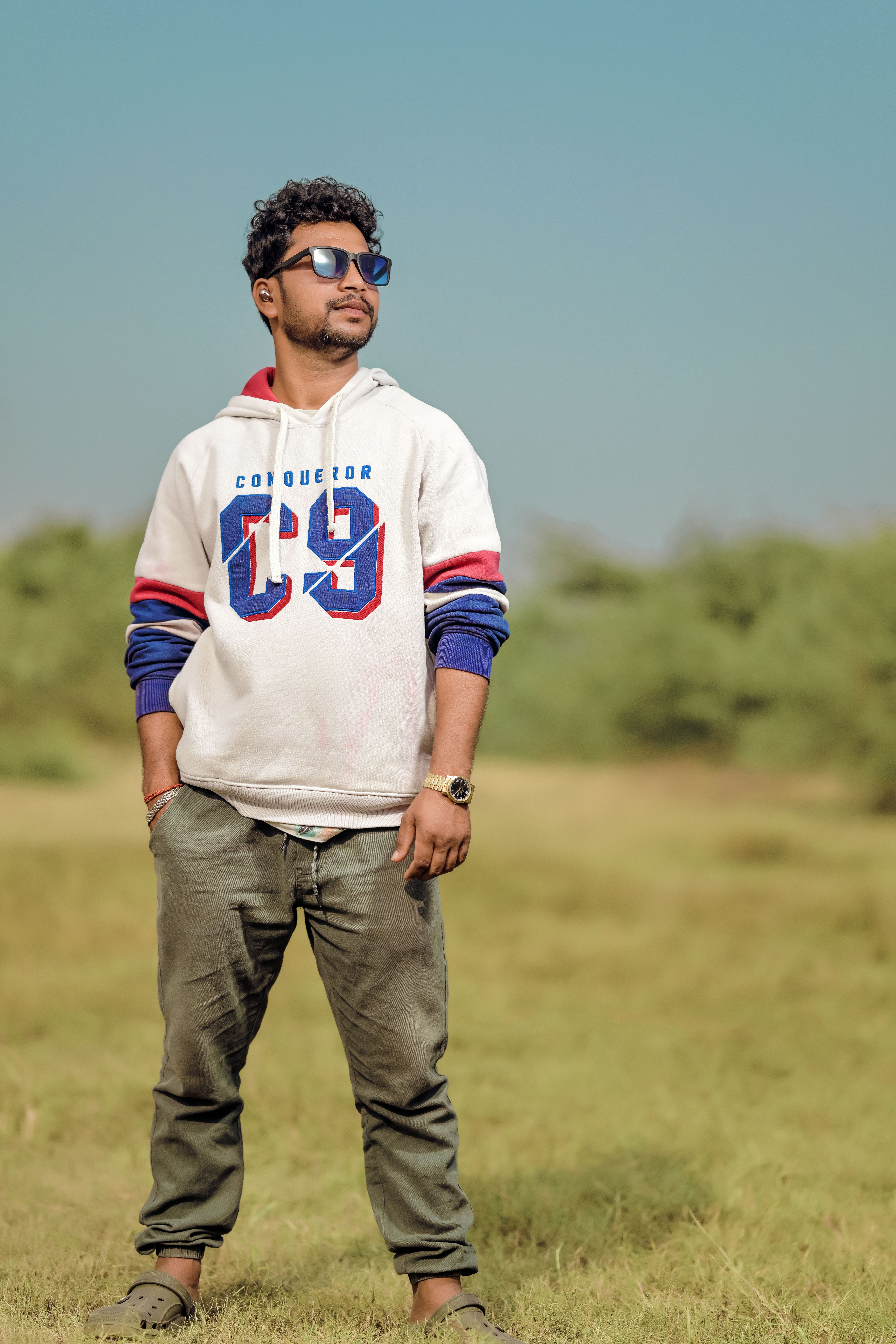 Young man in casual attire standing outdoors on a sunny day.