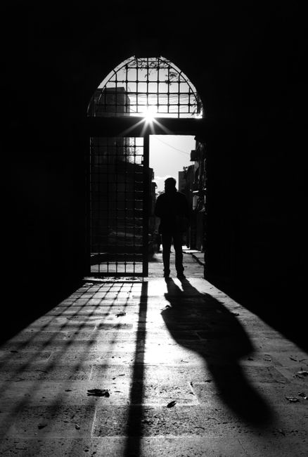 Black and white silhouette of a person in an ancient doorway in İstanbul, capturing dramatic shadows.