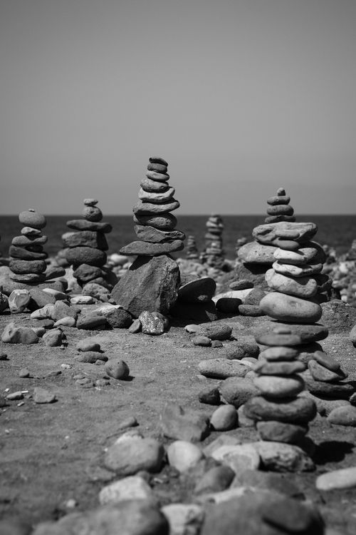 Free Artistic black and white photo of stacked stone cairns on a rocky beach Stock Photo