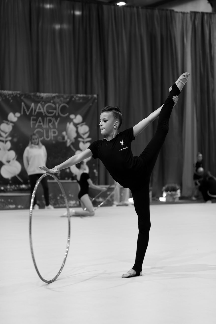 Jonge turnster voert een hoepeloefening uit bij de Magic Fairy Cup in de hal.