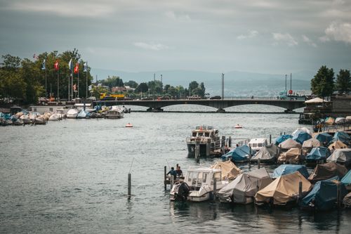 Free A peaceful view of anchored boats with a bridge in Zurich, Switzerland. Stock Photo