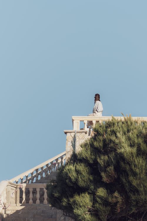 Free A person stands on an outdoor staircase with a balustrade, overlooking lush greenery under a clear sky. Stock Photo