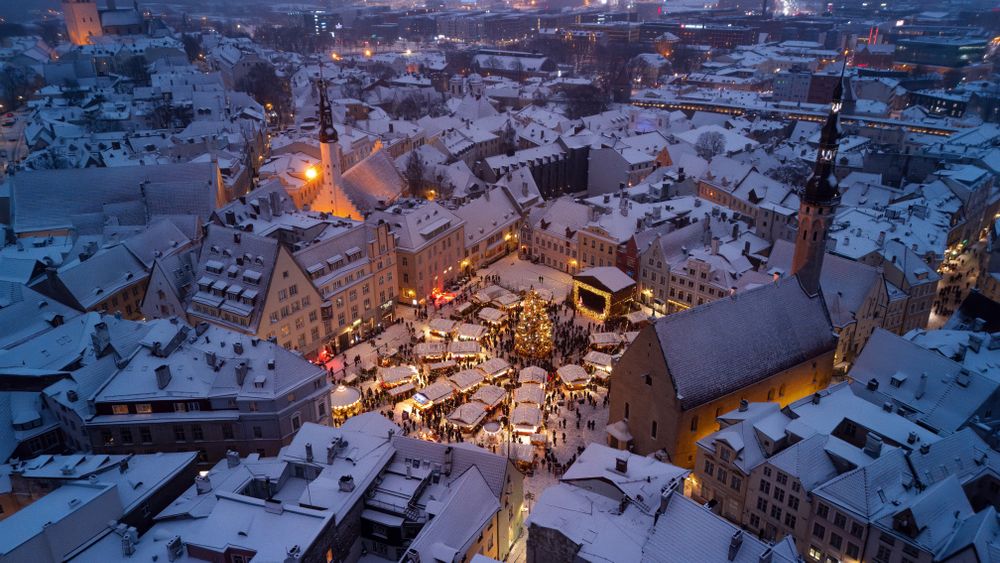 Vedere de sus asupra târgului de Crăciun din Tallinn, cu acoperișuri înzăpezite și lumini