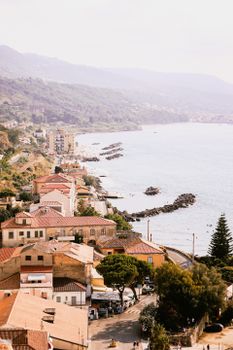 Charming Italian coastal town view with terracotta roofs and serene ocean waves.