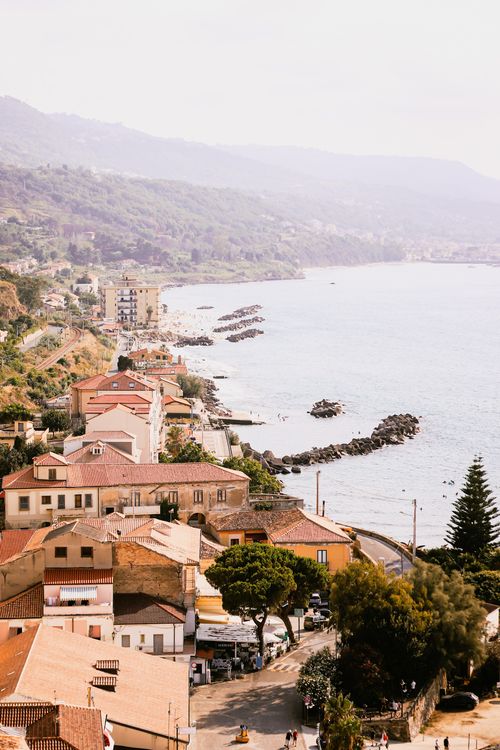 Free Charming Italian coastal town view with terracotta roofs and serene ocean waves. Stock Photo