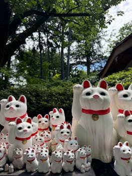A collection of Maneki Neko figurines in a tranquil outdoor setting, Tokyo.