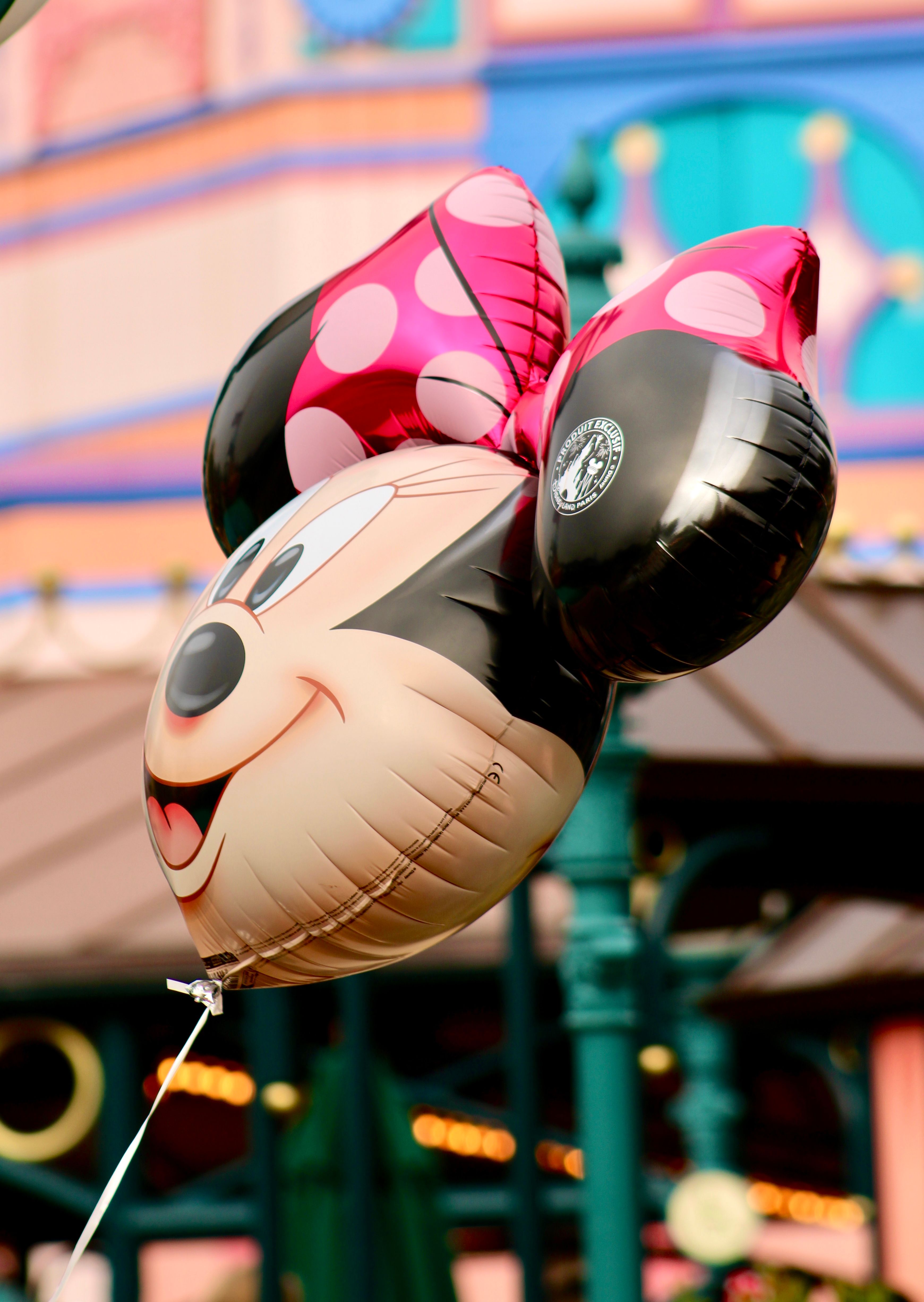 Vibrant balloon resembling a cartoon character at a lively amusement park setting.
