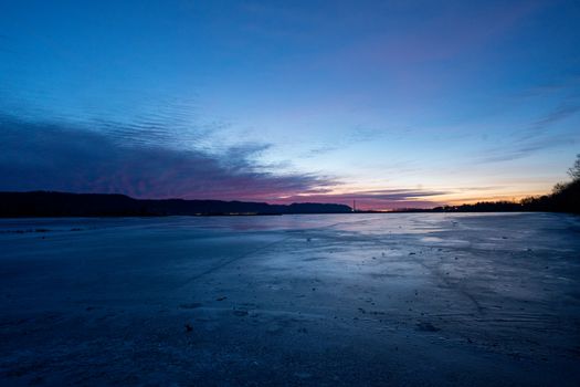 A serene winter dawn over a frozen lake in Wabasha, Minnesota, with vibrant skies.