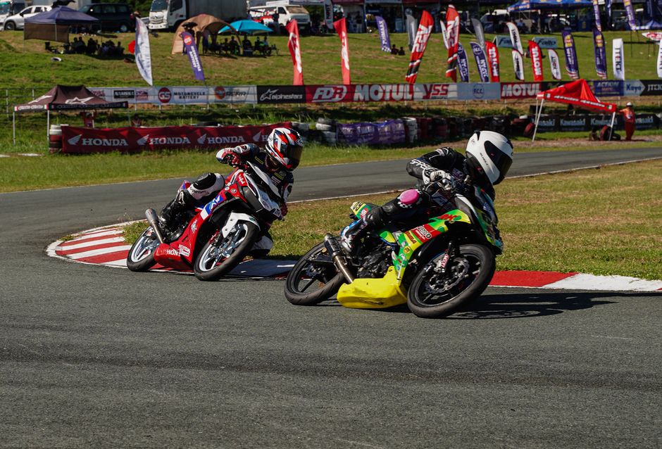 Two motorcyclists race on a curvy track in Tarlac City, Philippines, showcasing speed and skill.