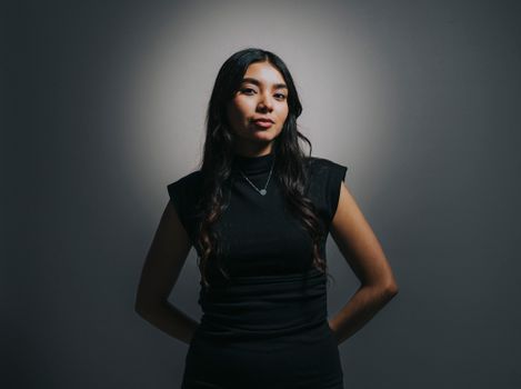 A confident young woman posing with studio lighting, creating a dramatic effect.