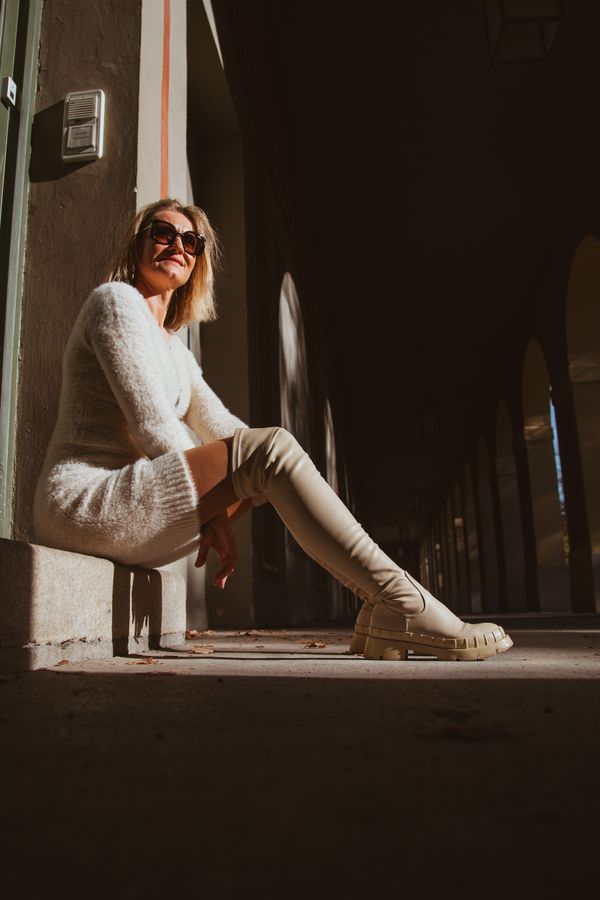 Woman in a ribbed knit sweater dress with knee-high boots