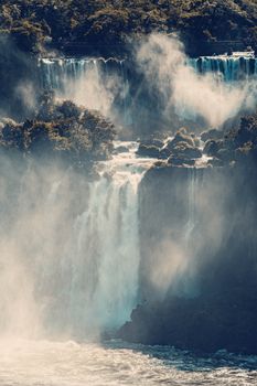 Dramatic view of Iguassu Falls cascading amidst lush greenery and mist.