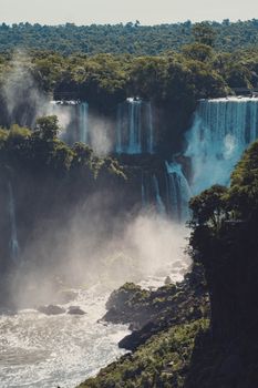 Stunning panoramic view of Iguazu Falls with cascading water amid dense green rainforest.