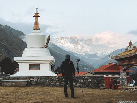 Photographer capturing scenic view in Kumjung, Nepal, with Everest backdrop and traditional architecture.