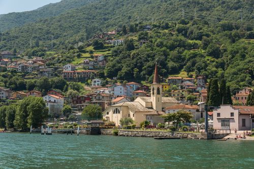 Free Picturesque village with a charming church by a serene lake in Lombardy, Italy. Stock Photo