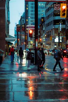 Urban street scene in Toronto during evening with reflections on wet pavement.
